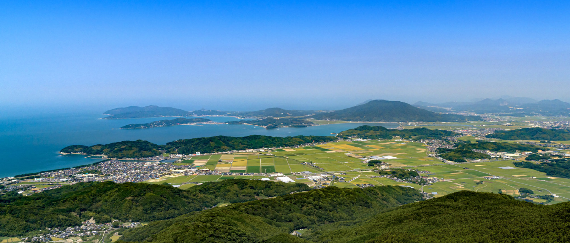 青空の下で笑顔を見せる親子三人