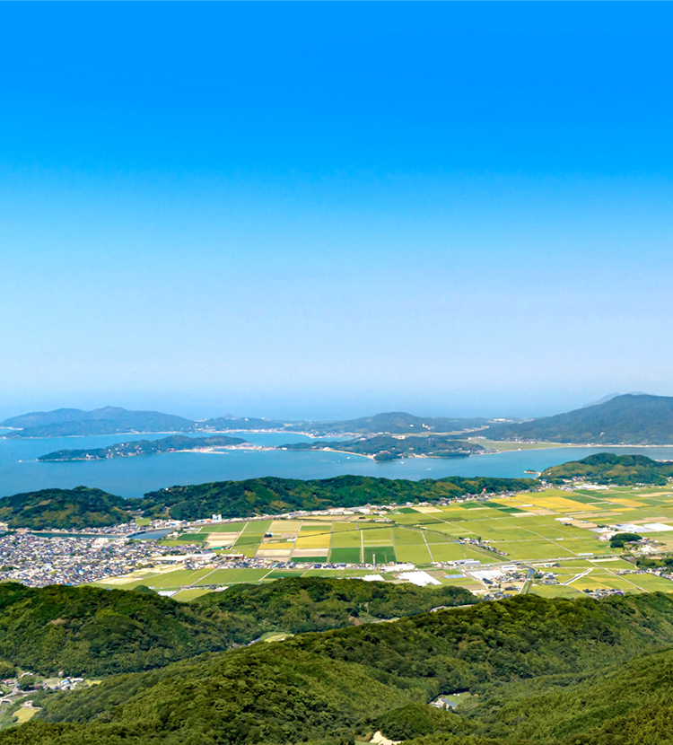 青空の下で笑顔を見せる親子三人